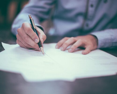 man's hands holding pen on paper